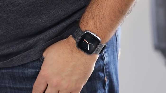 man wearing a fitbit versa connected watch on a blue strap